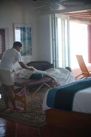 Ein Zimmer mit Massagetisch, einem Bett und einem Sessel.