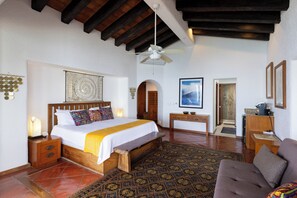 Ein Schlafzimmer mit einem hölzernen Bett, einem Deckenventilator, einem gemusterten Teppich und einem gerahmten Bild an der Wand.