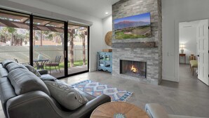 Una sala moderna con chimenea, televisor grande montado en la pared y un área de estar confortable con sofá y mesa de centro.