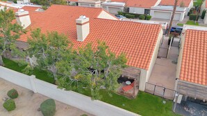 Zona residencial con techos de tejas rojas, entrada protegida por una reja y un pequeño patio.