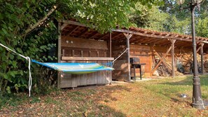 A wooden structure with a covered porch, a hammock, and a barbecue grill. - Villa Marilou: Quiet Location and Private Pool (Cestas)
