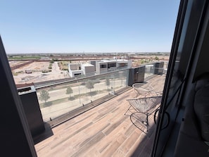 A balcony with a view of a construction site, modern buildings, and a clear sky.