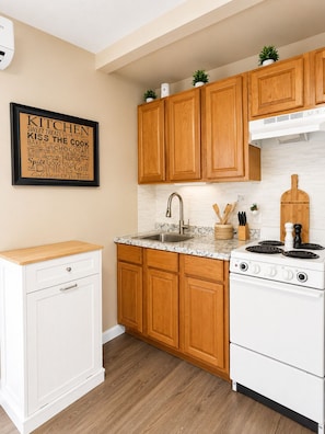 A kitchen with wooden cabinets, a white stove, a sink, and a countertop with a marble-like pattern.