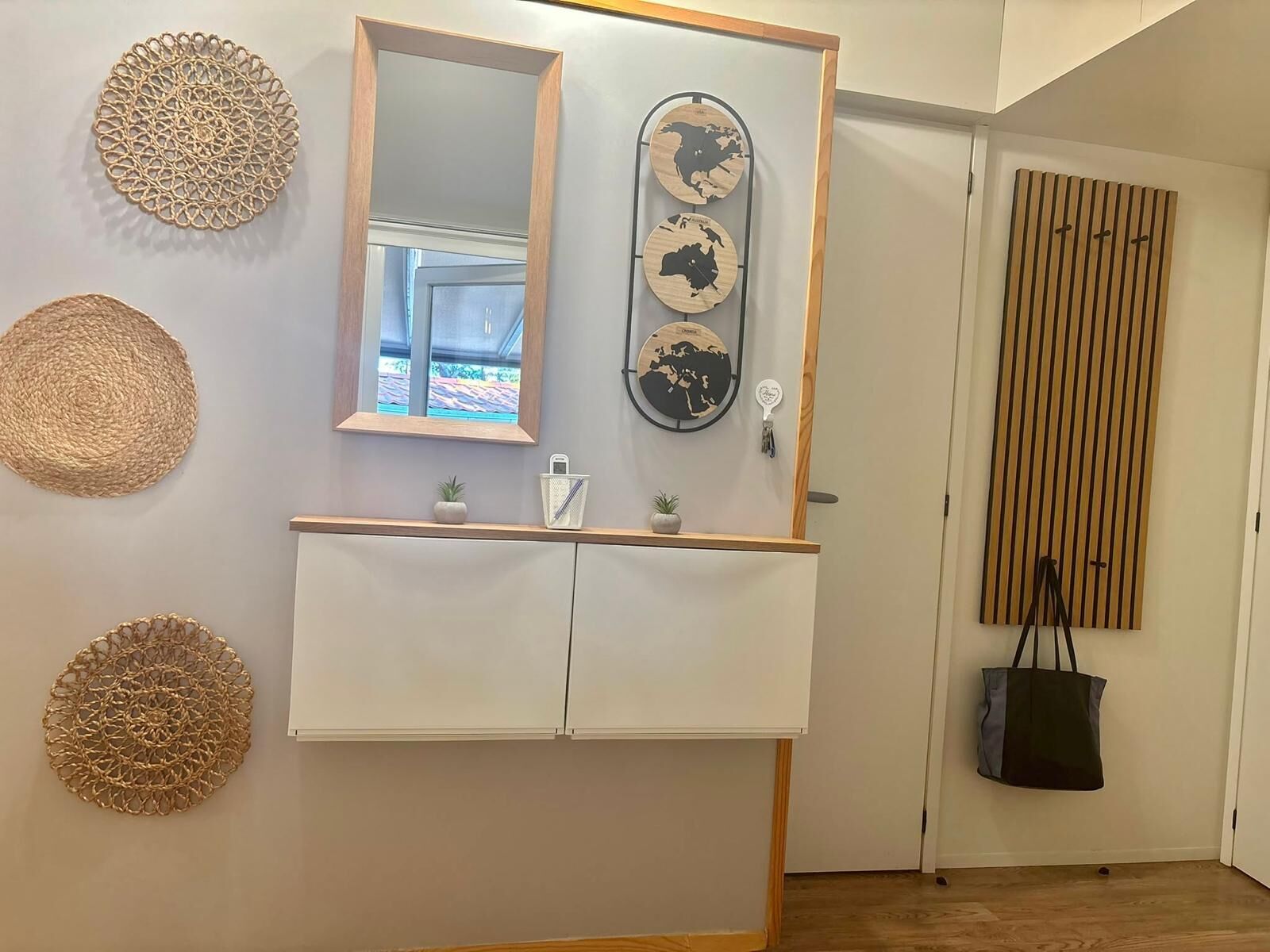 A room with a wooden-framed mirror, a white cabinet, and decorative wall hangings.