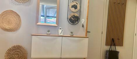 A room with a wooden-framed mirror, a white cabinet, and decorative wall hangings.