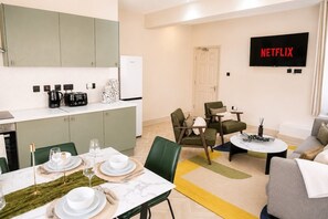 Ein zeitgemäßer Wohnraum mit Essbereich, Küche und einem Fernseher, der 'NETFLIX' zeigt.
