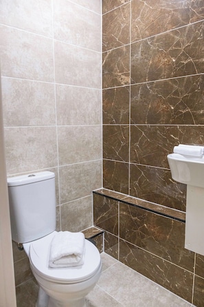 Et badeværelse med toilet, håndklædestang og en væg i marmor.