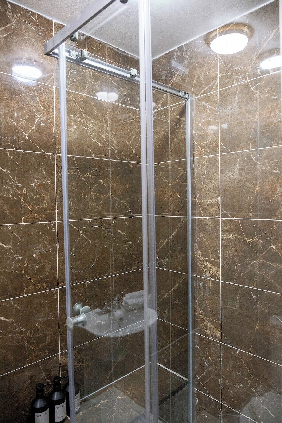 Eine gläserne Duschkabine mit Marmorwand.