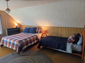 A bedroom with two beds, a wooden headboard, a lamp, and a patterned rug.