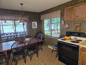 Una cocina con estufa, sillas, una mesa de comedor y vistas al exterior.