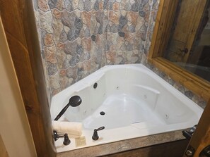 Un bagno con una parete in pietra, una vasca da bagno bianca e una porta in legno.