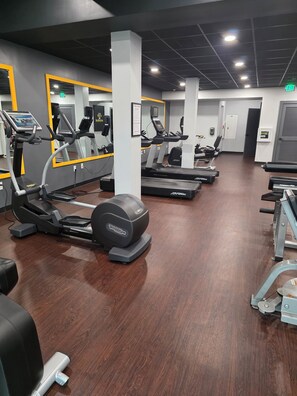 Una palestra con tapis roulant, ellittiche e attrezzature per pesi.
