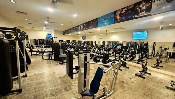 A gym with various exercise equipment, including treadmills and weight machines, arranged in rows.