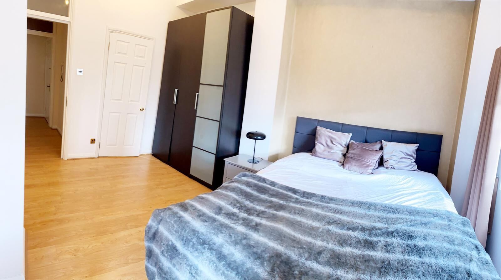 Een slaapkamer met een bed, nachtkastje en kledingkast.