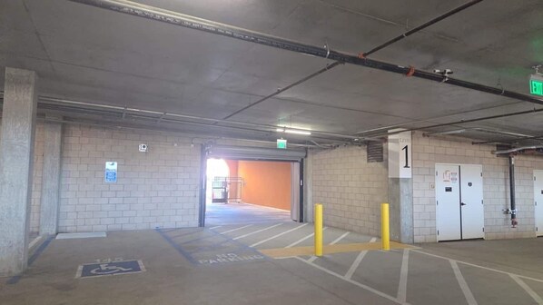 A parking garage with a wheelchair-accessible space marked, a fire exit, and a level indicator.