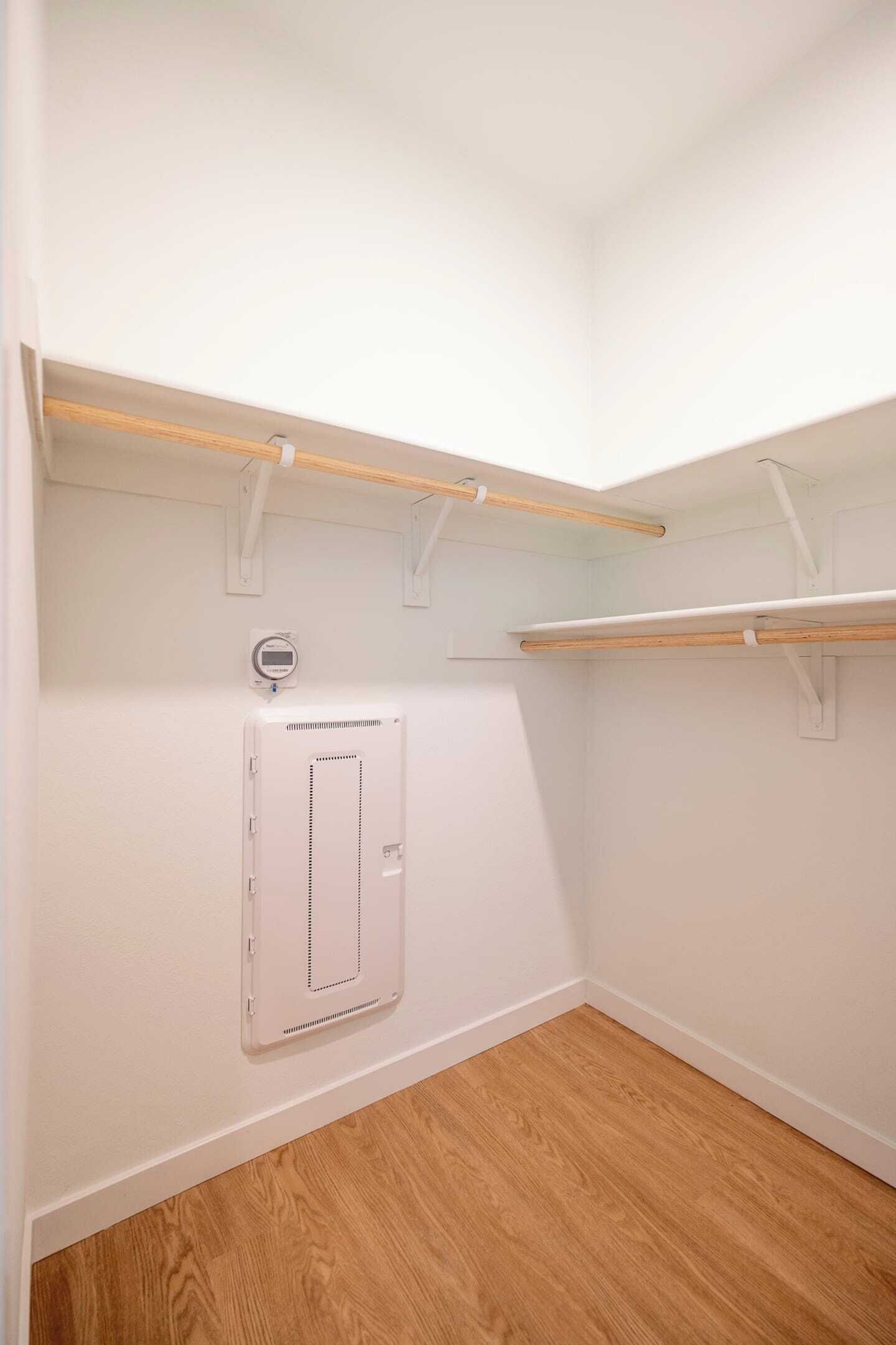 A corner closet with wooden shelves and a white electrical box.