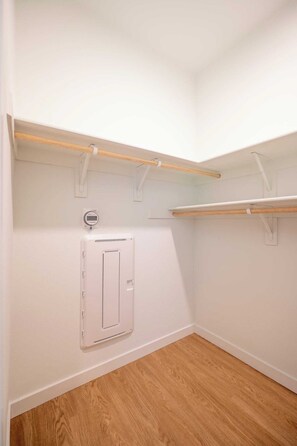 A corner closet with wooden shelves and a white electrical box.