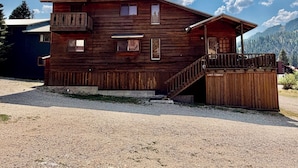 A wooden cabin with a balcony, a porch, and a staircase leading to the entrance. - Last Chance Cabin in Red River NM (Red River)