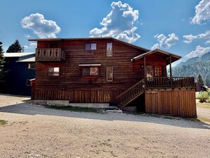 A wooden cabin with a balcony, a porch, and a staircase leading to the entrance. - Last Chance Cabin in Red River NM (Red River)