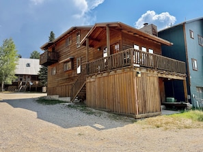 Una cabana de fusta amb un balcó, una escala i un camí d'accés de grava.
