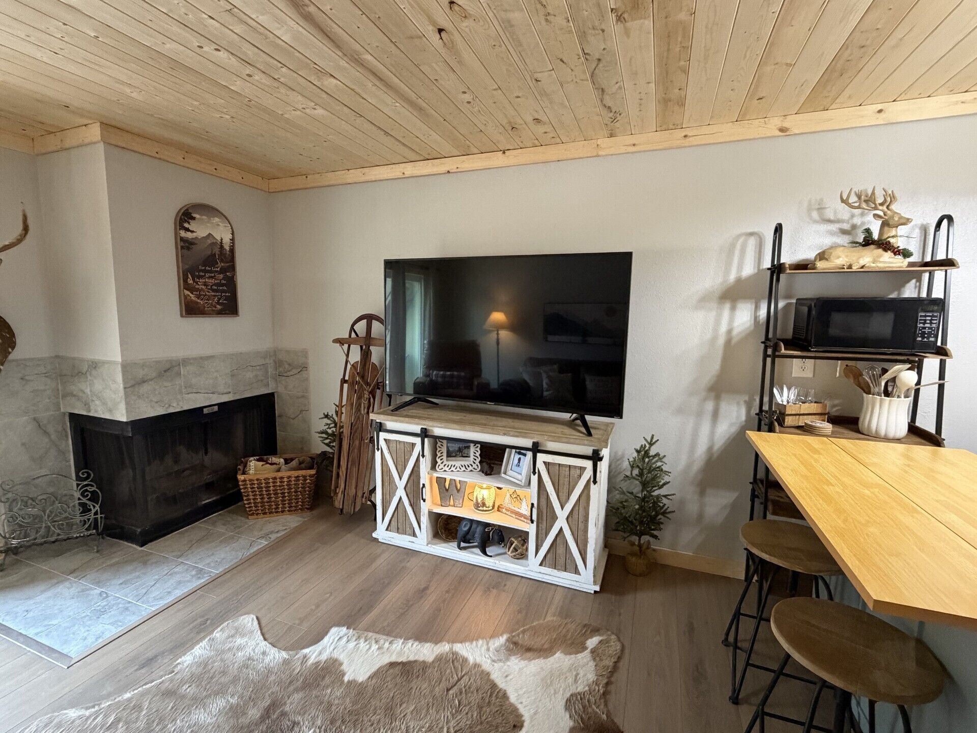A cozy living room with a fireplace, a television, and a wooden ceiling.