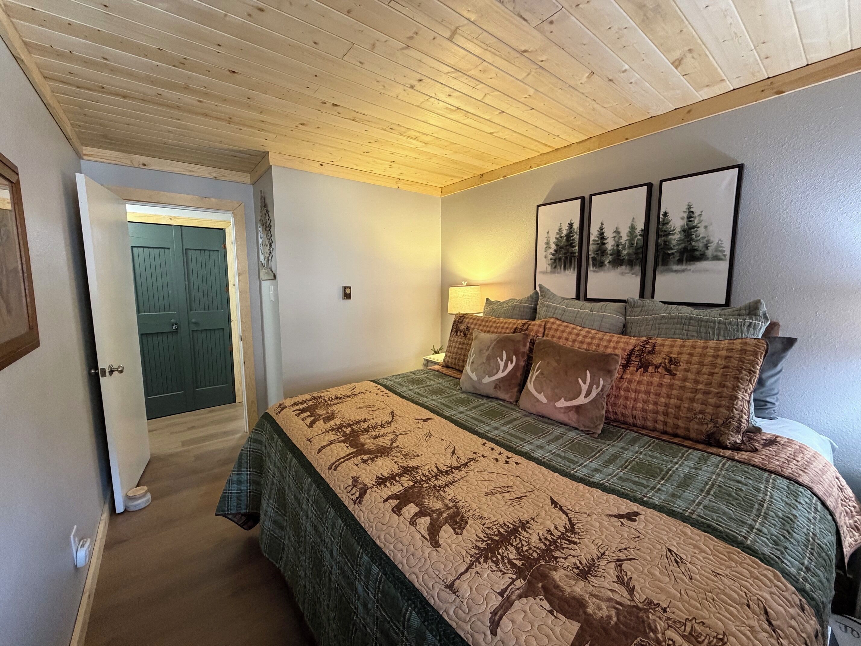 Une chambre à coucher avec un lit, une table de chevet, une lampe et des tableaux encadrés accrochés au mur.