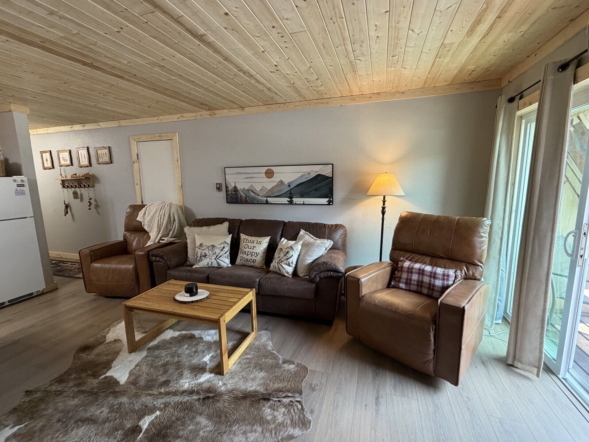 A cozy living room with a brown leather sofa, a wooden coffee table, and a fur rug.