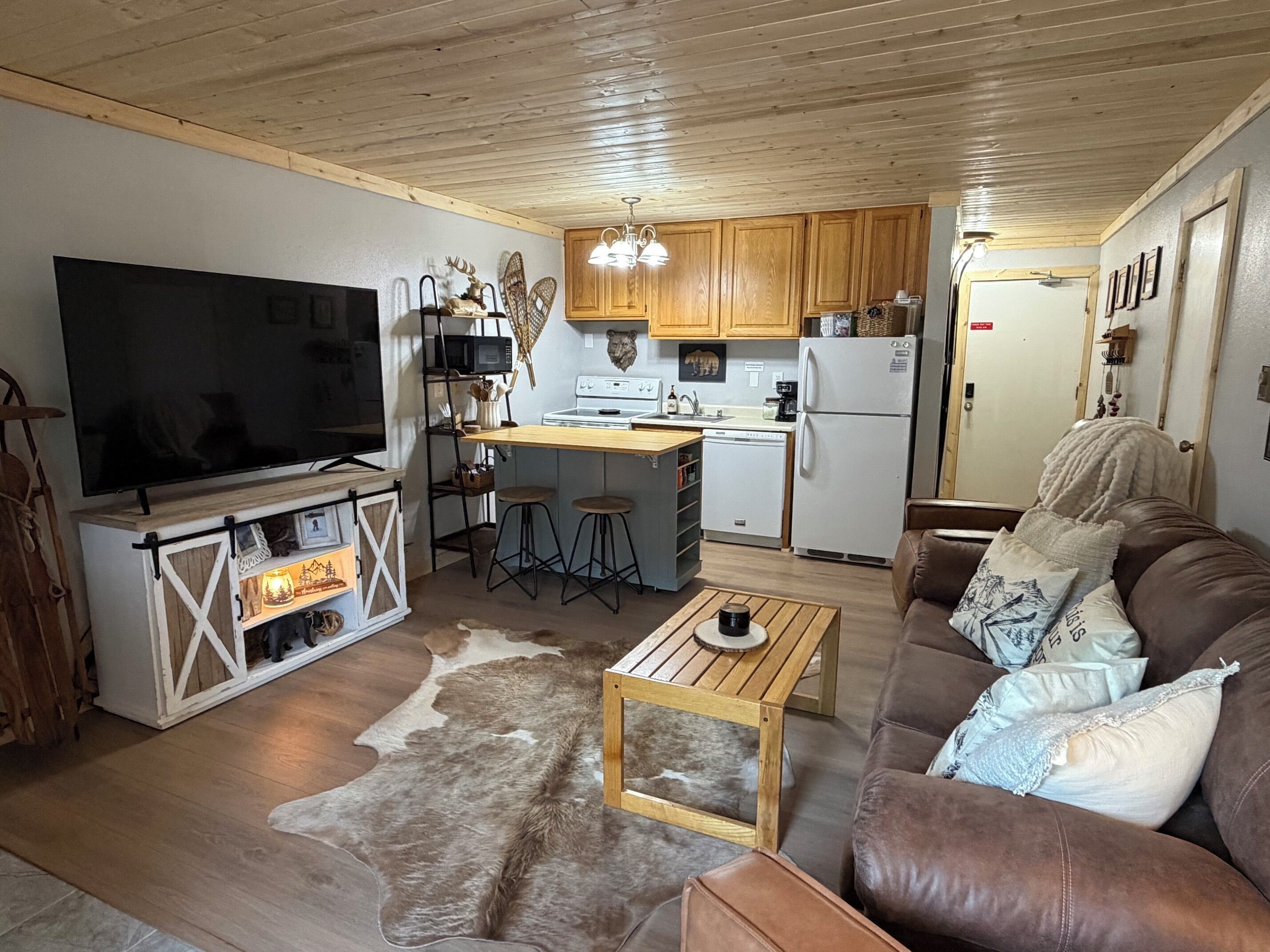 Un salon chaleureux avec un téléviseur, une table basse en bois et un canapé en cuir marron.