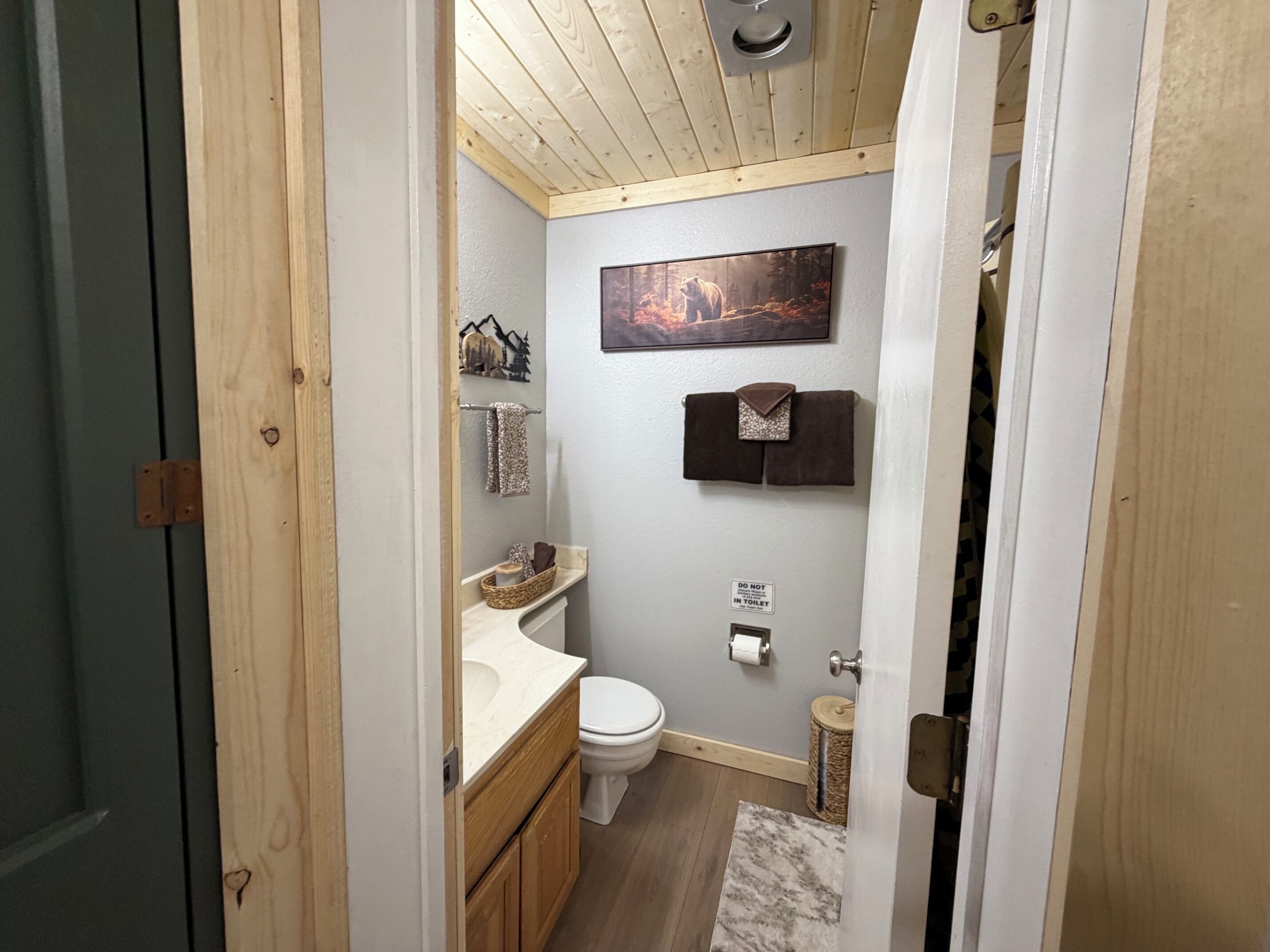 Un bagno con una porta in legno, un water, un lavandino e un portascopevoli.