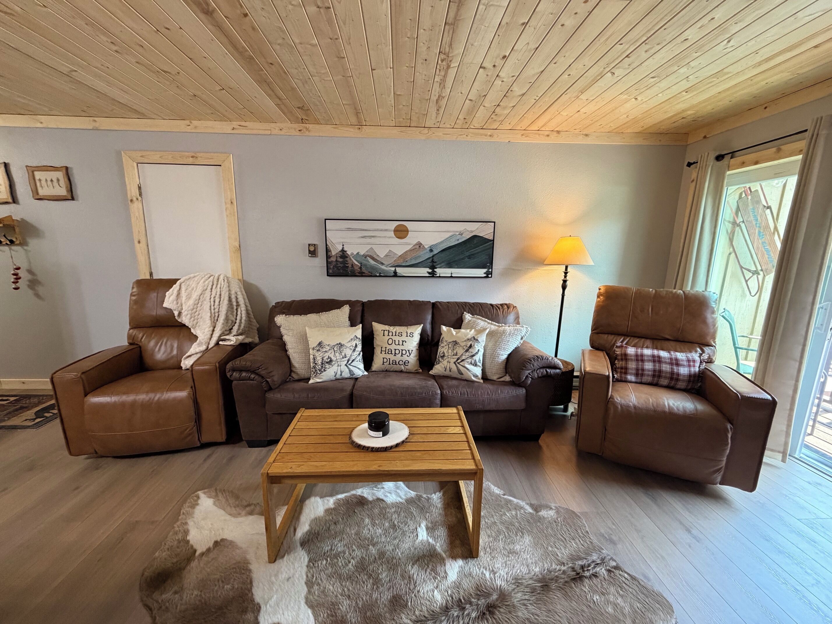 A cozy living room with a brown leather sofa, a wooden coffee table, and a fur rug.