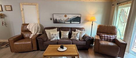 A cozy living room with a brown leather sofa, a wooden coffee table, and a fur rug.