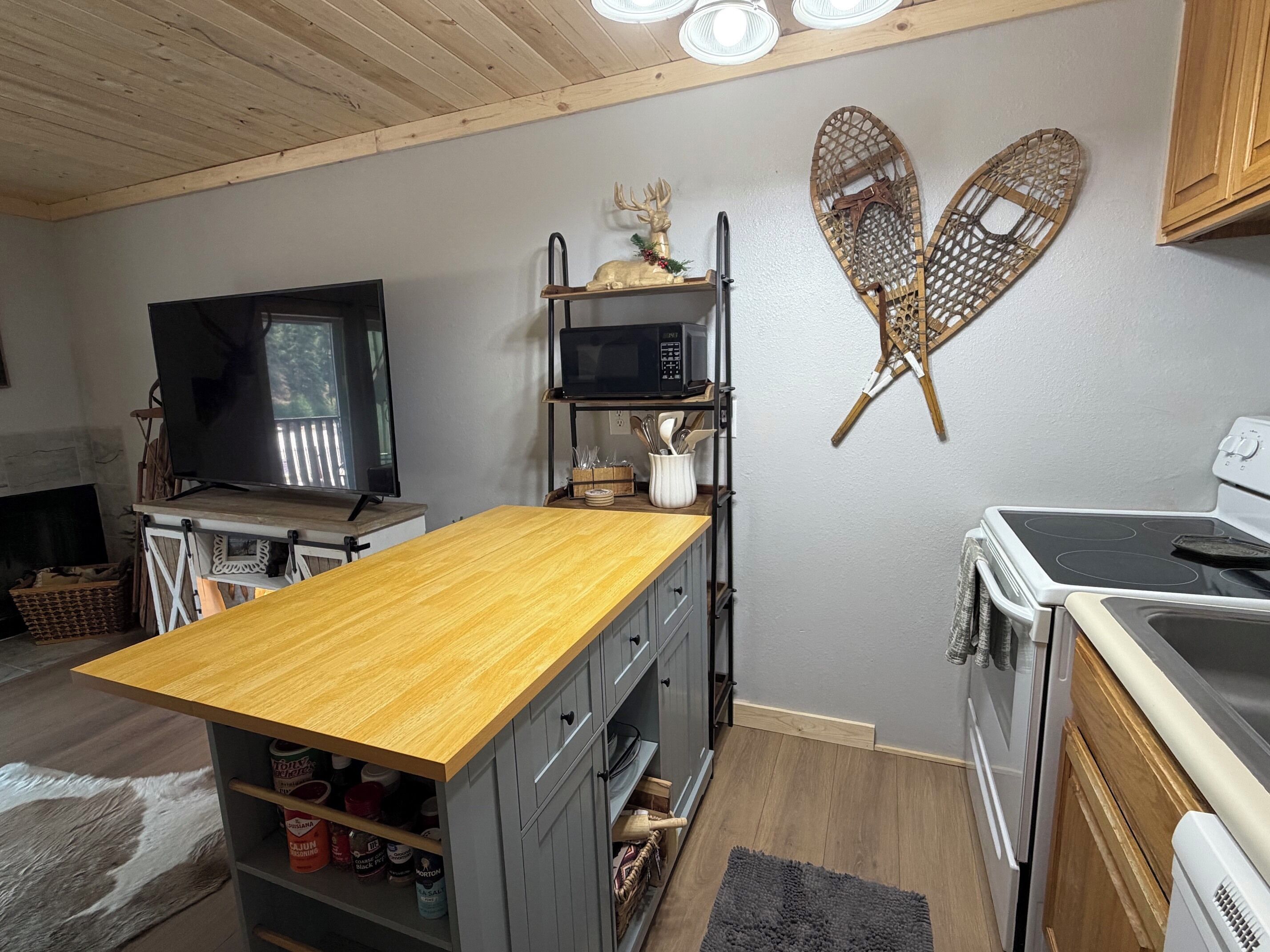 A compact kitchen with a wooden island, a microwave, and a stove.