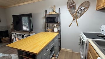A compact kitchen with a wooden island, a microwave, and a stove.