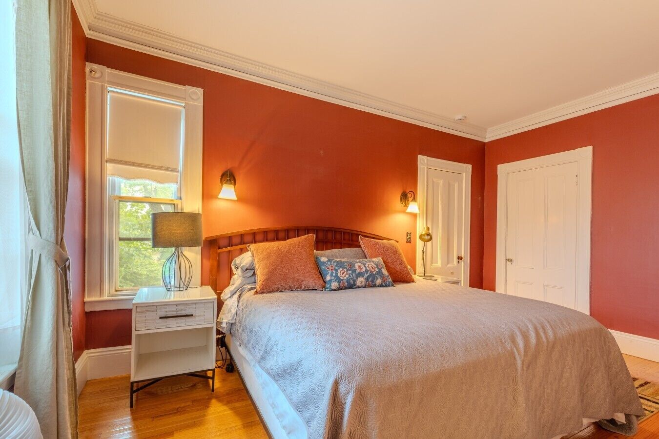 Een slaapkamer met een bed, nachtkastje, lamp en twee wandlampen.