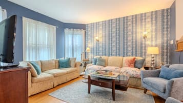 Un salon avec un canapé beige, un fauteuil bleu, une table basse et un téléviseur.
