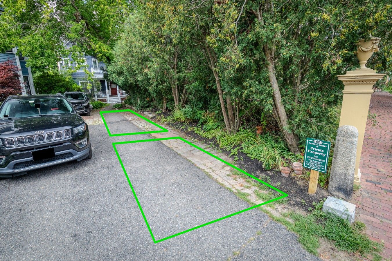 Een woonstraat met een geparkeerde Jeep, een groene afscheiding en een bord dat aangeeft dat het privé-eigendom is.