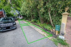 A residential street with a parked Jeep, a green boundary line, and a sign indicating a private property.