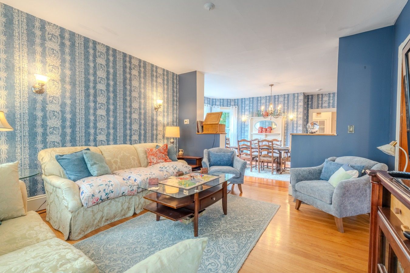A living room with a sofa, armchairs, a coffee table, and a dining area with a table and chairs.
