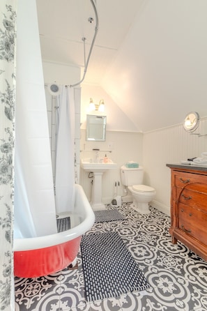 A bathroom with a freestanding bathtub, a sink, a toilet, and a vanity with a mirror.