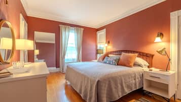 Una camera da letto con un letto, comodini, uno specchio e una finestra con tende.