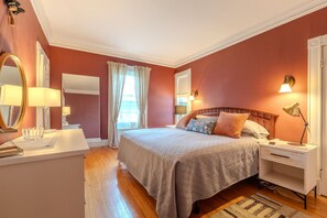 A bedroom with a bed, bedside tables, a mirror, and a window with curtains.