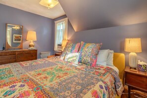 Un dormitorio con una cama grande, un aparador, un espejo y una ventana con cortinas.
