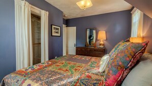 Um quarto com cama, cômoda e luminária no teto.