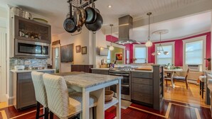 Uma cozinha moderna com ilha central, eletrodomésticos de aço inoxidável e iluminação pendente.