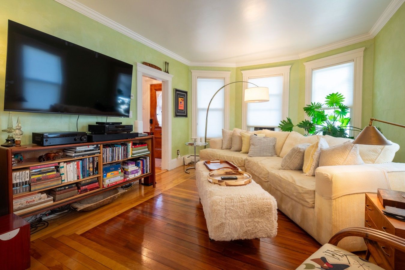 A living room with a flat-screen TV, a bookshelf, a beige sofa, and a coffee table.