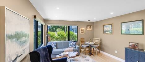A modern living room with a sofa, dining table, and artwork on the walls.