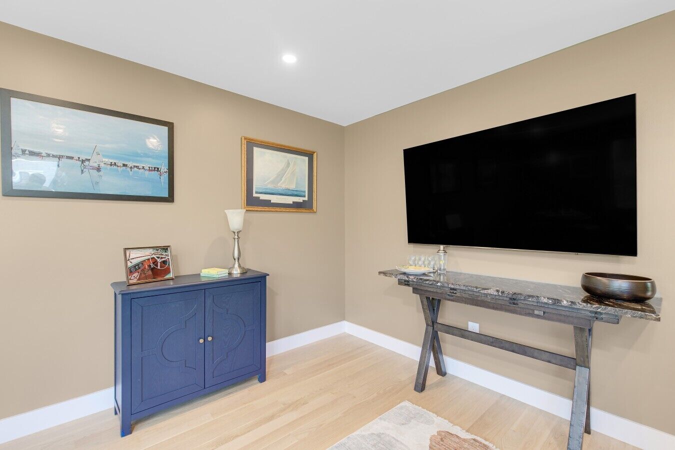 Una habitación con un armario azul, una mesa de mármol, un televisor de pantalla plana y dos cuadros en la pared.