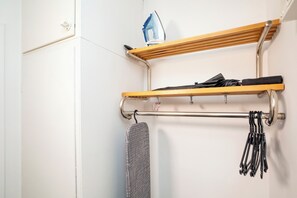 A bathroom with a towel rack, a hanging towel, and a shelf with a bottle and a pair of scissors.