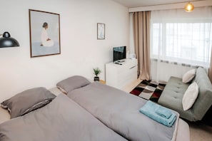 Ett hotellrum med två sängar, en tv, ett skrivbord och ett fönster med gardiner.