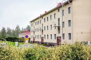 A multi-story building with a flat facade, multiple windows, and a red roof.